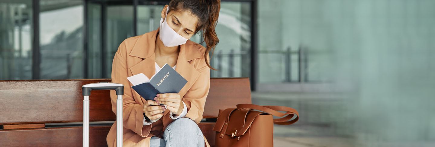 Woman with medical mask checking her passport at the airport during pandemic