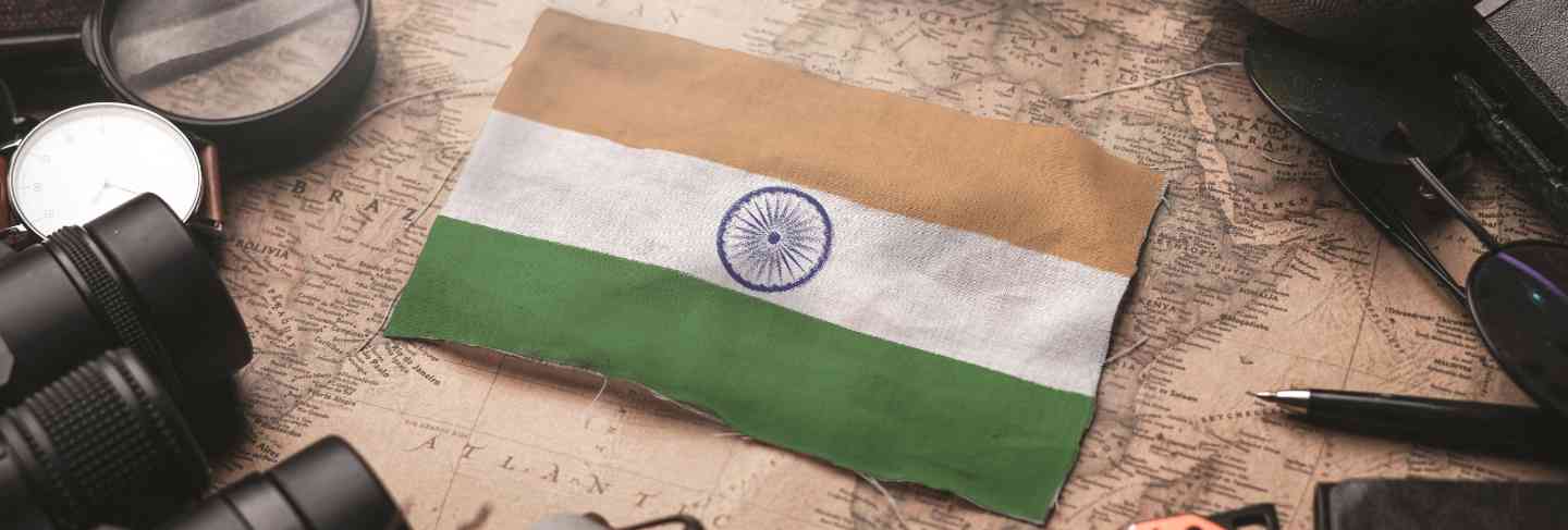 India flag between traveler's accessories on old vintage map. tourist destination concept.

