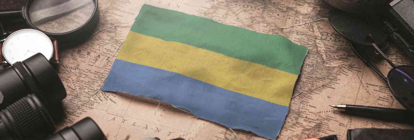 Gabon flag between traveler's accessories on old vintage map. tourist destination concept.
