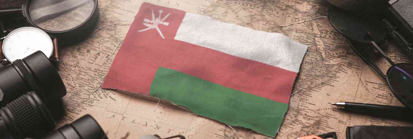 Oman flag between traveler's accessories on old vintage map. tourist destination concept.
